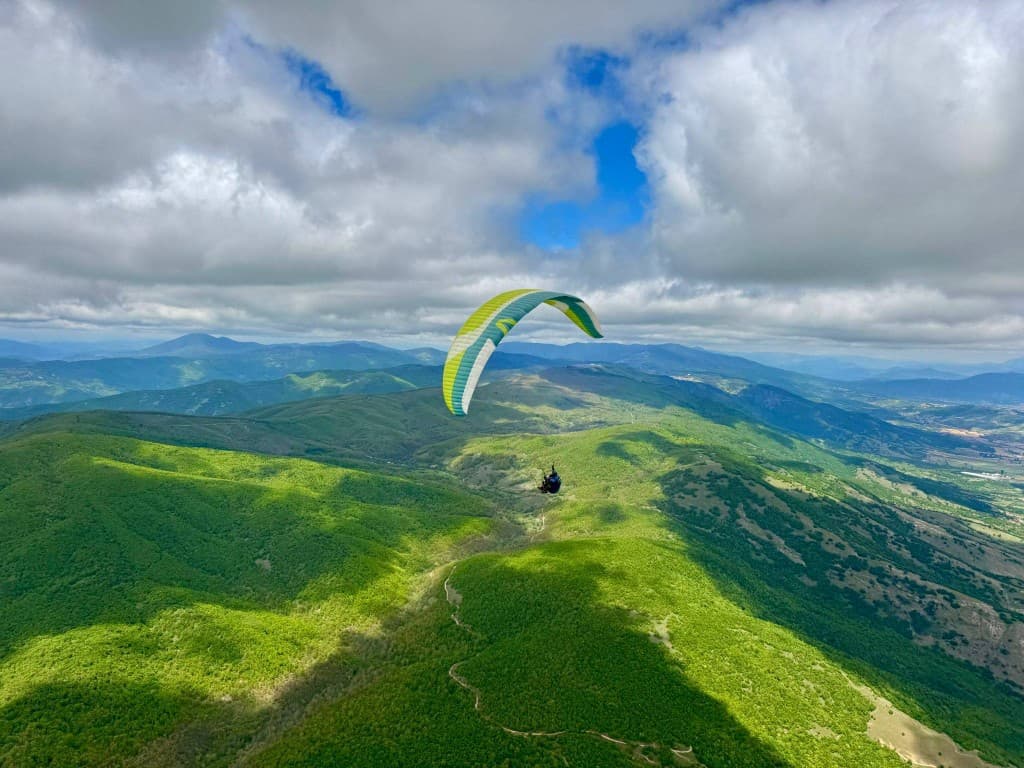 A colourful wing crossing a deep green valley